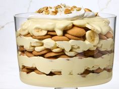 a layered dessert with bananas and cream in a glass dish