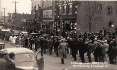 an old black and white photo of people walking down the street