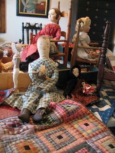 several dolls sitting on top of a bed in a room filled with furniture and rugs