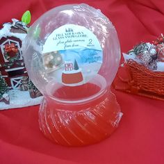 a snow globe sitting on top of a red tablecloth covered table next to christmas decorations