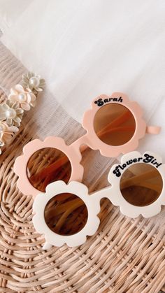 two pairs of sunglasses sitting on top of a wicker basket next to white flowers