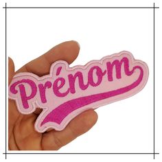 a hand holding a pink patch that says,'premn '