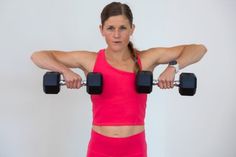 a woman holding two dumbbells in front of her face