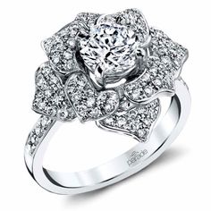 a white gold ring with an intricate flower design and round diamonds on the band, set in