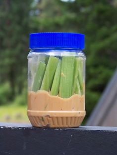 a jar filled with pickles sitting on top of a table next to a blue lid