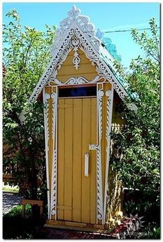 a small yellow and white building in the middle of trees