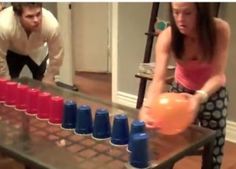 a man and woman are playing an interactive game on the coffee table with cups in front of them