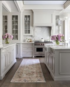 a large kitchen with white cabinets and marble counter tops, along with an area rug on the floor