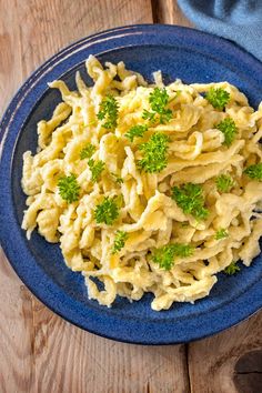 a blue plate topped with macaroni and cheese on top of a wooden table