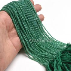 a hand holding some green seed beads