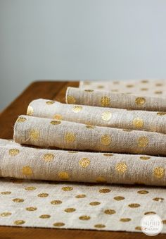 four pieces of fabric with gold polka dots on them sitting on a wooden table top