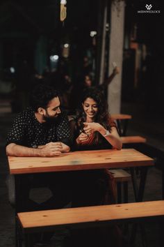 a man and woman sitting at a table looking at their cell phones in the dark