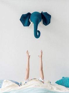 a person laying in bed with an elephant head on the wall above their head,