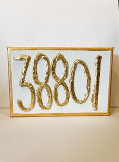 a close up of a number on a sign with gold foil paint and numbers in the middle