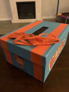 an orange and blue box sitting on top of a wooden table next to a fireplace