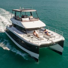 two people are sitting on the back of a boat in the open water while another person is driving behind them