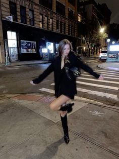 a woman is running across the street in her boots and dress, with one leg spread out