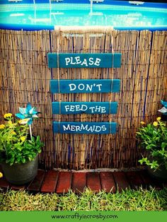 a sign that says please don't feed the mermaids next to some flowers