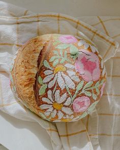 a piece of bread sitting on top of a white cloth covered in flowers and leaves