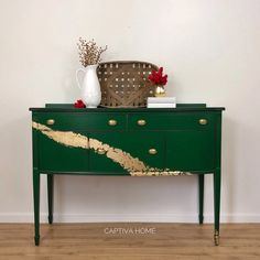 a green dresser with gold paint on it and a vase sitting on top of it