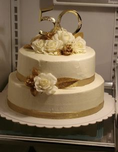 a white cake with gold decoration and flowers