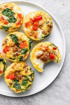 a white plate topped with mini frittatas filled with meat and vegetables next to a person's hand