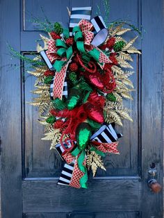 a christmas wreath on the front door with red, green and black ribbons hanging from it