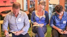 three people sitting in chairs looking at papers