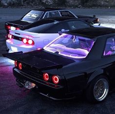 two cars parked next to each other in a parking lot with lights on the hoods