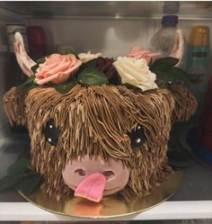 a cake shaped like a cow with flowers on it's head and tongue sticking out