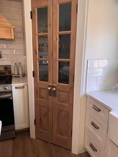 a kitchen with white cabinets and wooden doors