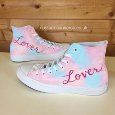 a pair of pink and blue sneakers with the word love written on them, sitting on top of a table