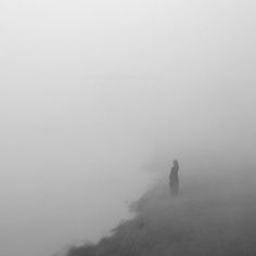 a person standing on top of a hill covered in fog