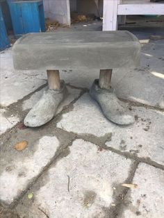 a concrete bench sitting on top of a stone floor next to a blue door with two feet sticking out of it