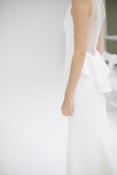 the back of a woman's white dress with ruffles and pearls on it