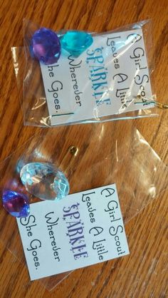 two plastic bags filled with different colored beads on top of a wooden table next to each other