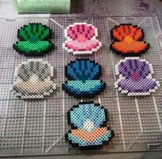 six perlercrafted pieces of different colors and shapes on a table with scissors