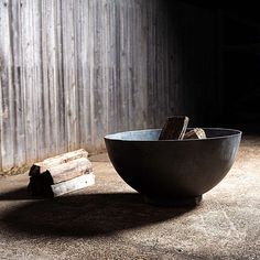 a bowl sitting on the ground next to a piece of wood