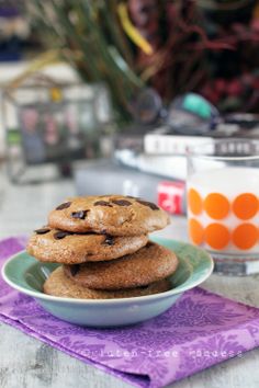 a stack of chocolate chip cookies sitting on top of a purple napkin next to a glass of milk