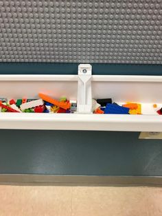 a shelf filled with legos on top of a tiled floor next to a wall