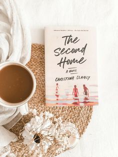 a cup of coffee next to a book about the second home by christian clavey