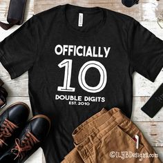 10th Birthday Shirt - Officially 10 Double Digits Birthday Shirt - Tenth Birthday ShirtCelebrate this milestone birthday with a stylish DOUBLE DIGITS t-shirt. You have the option to customize with your child's name on the front or have the word "officially" instead of the name.SIZE:•XS youth•S youth•M youth•L youth•XL youthT-SHIRT COLOR:•black•gray•red•navyLETTER COLOR:•whitePERSONALIZATION:•personalize with any name above the number 10 on the front•if you do not want a name on the shirt, "offic Customizable Black T-shirt For Anniversary, Casual Black Top For Anniversary, Black Casual Top For Anniversary, Casual Name Print T-shirt For Anniversary, Casual T-shirt With Name Print For Anniversary, Black Graphic Tee For Birthday Gift, Black Graphic Print T-shirt For Anniversary, Black T-shirt For Birthday And Father's Day, Casual Black T-shirt For Anniversary