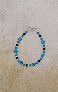 "one of a kind evil eye bracelet, cute evil eye bracelet for teens, blue crystal jewelry Sterling Silver, Glass and Glass Crystal Handmade beaded Bracelet, 7.\".  Round 2mm beads are sterling silver, 4mm bicone beads are glass crystal aquamarine and opaque black. Evil eye beads are flat coin shape 5mm glass. toggle clasp is pewter. evil eye jewelry is designed to protect the wearer from evil and ward off the evil that has been directed at them. Wearing any piece of jewelry with the evil eye symbol on it provides the wearer with both power and protection against evil spirits or bad luck. Check out my other jewelry at https://loveofjewelryshop.etsy.com" Blue Evil Eye Round Bracelets, Blue Round Evil Eye Bracelets, Adjustable Blue Evil Eye Bracelet Nickel Free, Adjustable Blue Evil Eye Bracelet, Nickel Free, Adjustable Nickel-free Blue Evil Eye Bracelet, Turquoise Bracelets With Evil Eye Round Beads, Turquoise Evil Eye Bracelet As Gift, Turquoise Evil Eye Bracelet Jewelry, Blue Hypoallergenic Evil Eye Bracelet As Gift