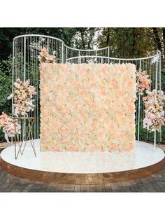 a floral backdrop is set up in front of an iron gate with pink and white flowers on it