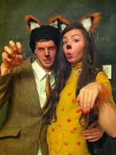 a man and woman dressed up as foxes posing for a photo together in front of a blackboard