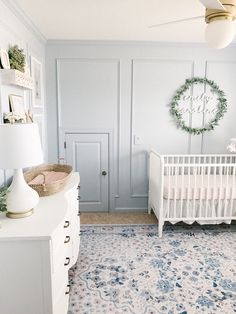 a baby's room with a white crib, dresser and wall hangings