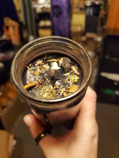 a person holding up a glass filled with liquid and gold flakes on top of it