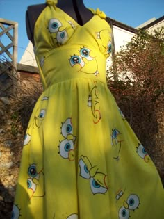 a yellow dress with blue eyes and an eyeball design on it, sitting on a mannequin