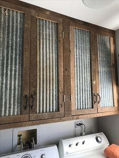 a washer and dryer in a room with wooden cabinet doors on the wall