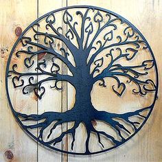 a metal tree with hearts on it is mounted to a wooden wall in the shape of a circle